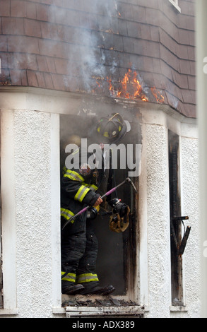 Pompiers Pompiers à la recherche d'un feu car il brûle au-dessus d'eux au cours d'une chambre d'urgence-incendie Banque D'Images