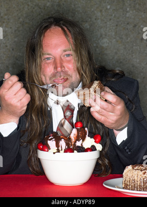 Gros homme aux cheveux longs manger bouche lui-même avec de la crème glacée Banque D'Images