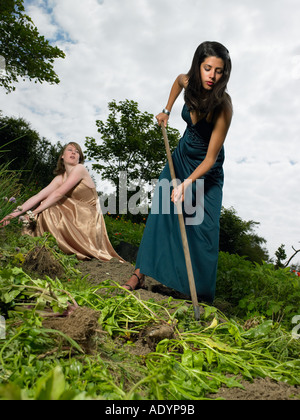 Deux jeunes femmes en tenue de soirée jardinage légumes Banque D'Images