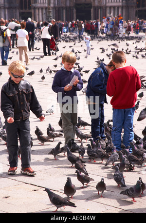 Enfants jouant avec les pigeons de la place St Marc Banque D'Images