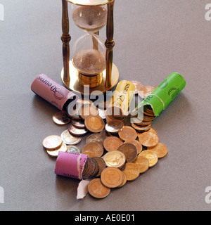 ROULEAUX DE PIÈCES DE MONNAIE EUROPÉENNE EN EUROS ET HOURGLASS AVEC SABLE TOMBANT Banque D'Images