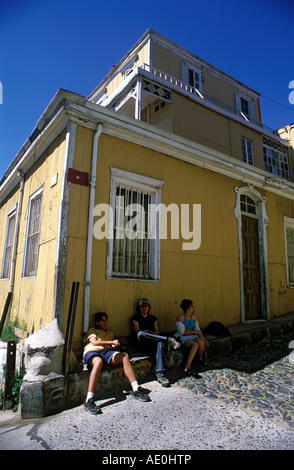 Trois adolescents s'asseoir sur les marches d'un revêtement en tôle ondulée, maison dans la banlieue de la colline Cerro Conception, Valparaiso, Chili. Banque D'Images