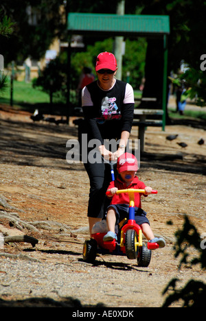 Mère poussant sur un vélo enfant jouet Banque D'Images