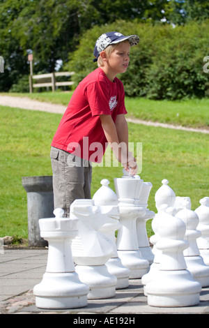 Garçon jouant avec un grand jeu d'échecs en plein air Banque D'Images