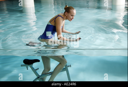 Young woman on exercise bike in spa pool Banque D'Images