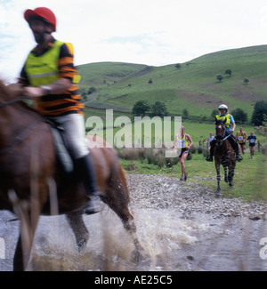 Des chevaux, des cavaliers et des gens courir traversant la Abergwesyn Ford à l'homme contre l'course de chevaux à Llanwrtyd Wells dans Powys Pays de Galles UK Banque D'Images