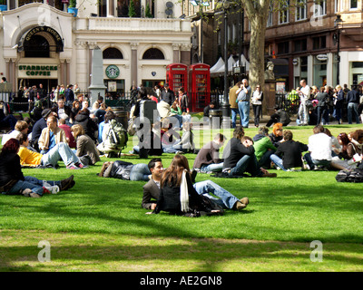 Les gens de détente sur pelouse Leicester Square Park Londres Angleterre Banque D'Images