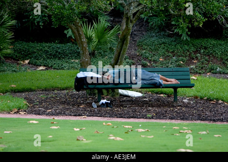 Sans-abri transitoire homme endormi sur un banc de parc de la ville Banque D'Images