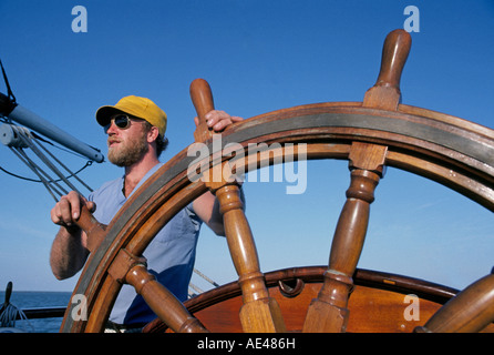 Un marin est à la roue en bois du navire à voile gréé carré Elissa comme elle quitte le port de Galveston Texas Banque D'Images