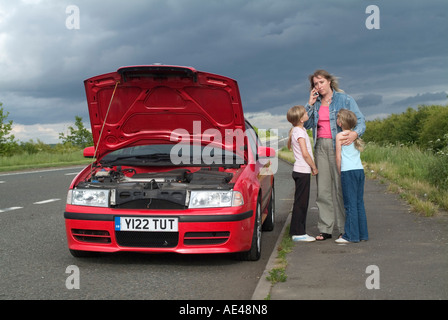 Famille au bord de la route avec panne de voiture demande d'assistance sur un téléphone mobile. Banque D'Images