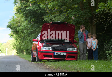 Famille au bord de la route avec panne de voiture demande d'assistance sur un téléphone mobile. Banque D'Images