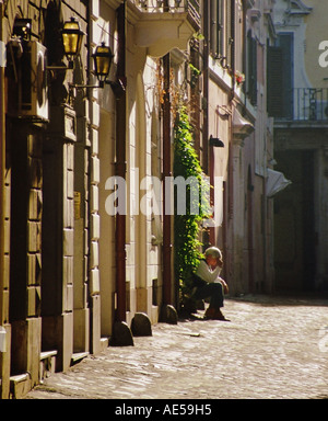 L'homme âgé assis sur une porte dans une rue de Venise, Italie Banque D'Images