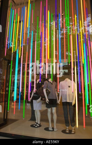 L'affichage de la fenêtre colorée dans un magasin de vêtements avec trois mannequins et de nombreux tubes verticaux de néons colorés Banque D'Images