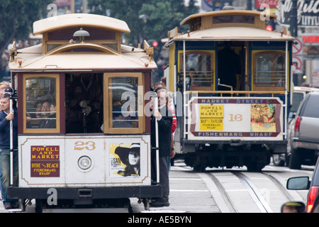 Deux téléphériques sur Powell et Market ligne passe sur Powell Street occupé en tant que touristes stand et accrocher sur Banque D'Images