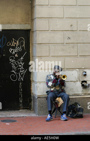 Homme noir jouant de la trompette sur une rue avec des graffitis sur une porte dans le quartier français de La Nouvelle-Orléans en Louisiane Banque D'Images