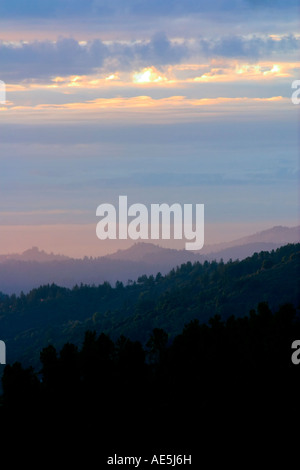 Grâce à la pointe soleil nuages dans le ciel tel qu'il définit plus de couches de la montagne Santa Cruz Mountains en Californie Banque D'Images