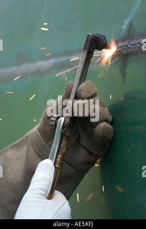 Gants soudeur à l'aide de torche s à couper à travers un réservoir en métal Banque D'Images