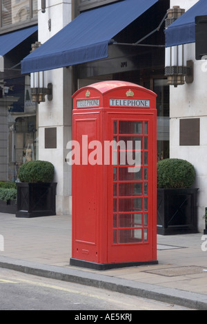 La cabine téléphonique rouge classique sur le trottoir en face d'un bâtiment avec auvents bleus à Londres en Angleterre Banque D'Images