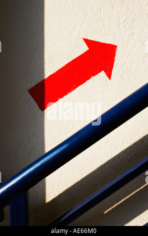 Flèche rouge one way sign peints sur le mur à côté d'escalier Banque D'Images