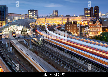 Un flou de trains à l'arrivée ou au départ de la gare de Waterloo de Londres au crépuscule pendant les heures de pointe. Banque D'Images