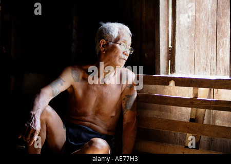 Vieil homme assis dans la longue piscine véranda de Rumah Uluyong, une longue maison traditionnelle Iban, Kapit, Sarawak, Bornéo, Malaisie Banque D'Images