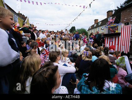 Enfants foule autour d'un Punch et Judy show lors d'une fête de rue d'été dans le village de Suffolk Boxford Banque D'Images