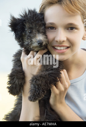 Girl holding puppy jusqu'à côté de face, portrait Banque D'Images