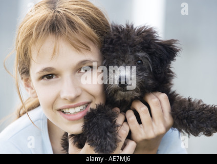 Girl holding puppy jusqu'à côté de face, portrait Banque D'Images