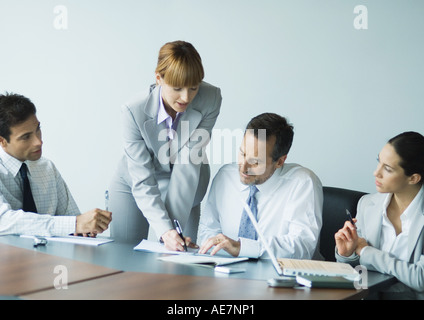 Businesswoman standing, parlant à ses collègues assis Banque D'Images