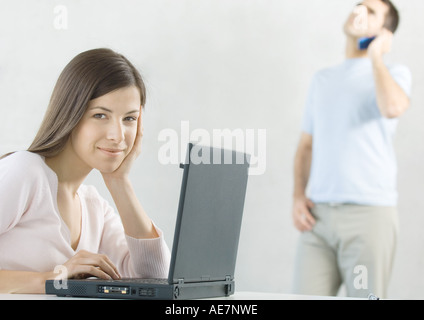 Woman using laptop while mari utilise le téléphone cellulaire en arrière-plan Banque D'Images