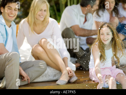 Girl splashing water, family relaxing in background Banque D'Images