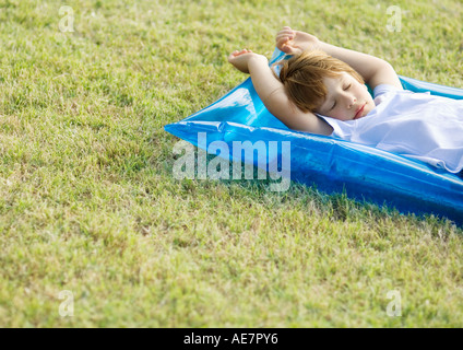 Petit garçon dormir sur radeau pneumatique, sur l'herbe Banque D'Images