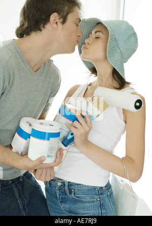 Couple holding painting supplies et Baisers Banque D'Images