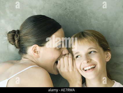 Young woman whispering pour fille, les deux rient, portrait, close-up Banque D'Images
