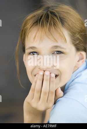 Girl couvrant la bouche looking at camera, smiling, portrait, close-up Banque D'Images