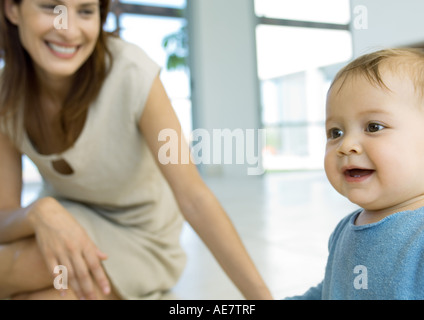 Woman smiling and watching baby Banque D'Images