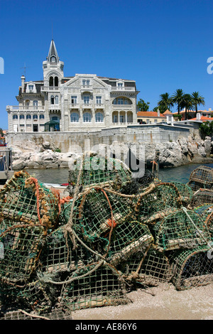 Des casiers à homard empilés sur les quais avec des propriétés en bord de mer dans le port de Cascais, près de Lisbonne, Portugal Banque D'Images
