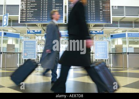 Portrait of businessman pulling luggage in airport Banque D'Images