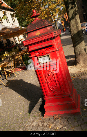 Old style red letter box mail box sur trottoir avec café à l'extérieur en arrière-plan Bruges Belgique Banque D'Images