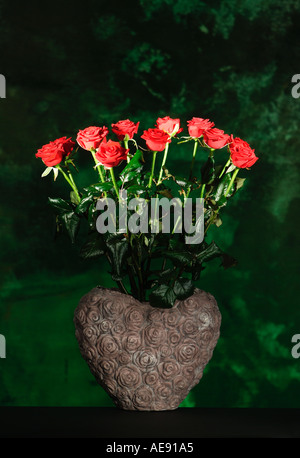 Une douzaine de roses rouges dans un vase en forme de coeur Banque D'Images