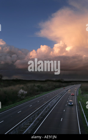Les voitures sur la route à deux carrageway avec les nuages de tempête , en Angleterre. Banque D'Images