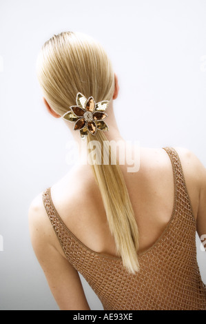 Jeune femme, vue de l'arrière, glisser dans ses cheveux blonds (studio) Banque D'Images