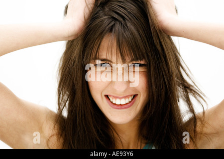 Portrait d'une jeune femme, les mains sur les cheveux bruns (studio) Banque D'Images