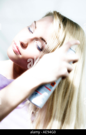 Portrait d'une jeune femme à l'aide de la laque pour cheveux Banque D'Images