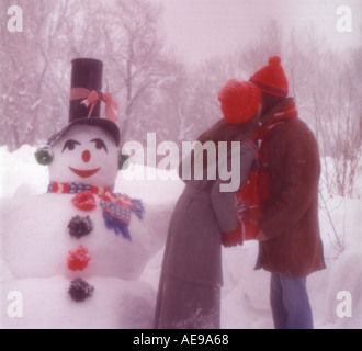 Neige d'hiver avec scène de Noël Bonhomme de neige souriant et de couple tout en maintenant des armload enveloppés de vacances présente Banque D'Images