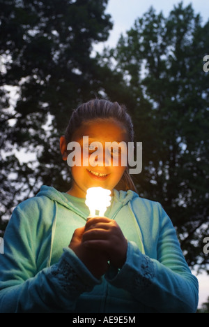 Girl holding une lampe fluorescente Lampe à économie d'énergie à l'extérieur dans ses mains Banque D'Images