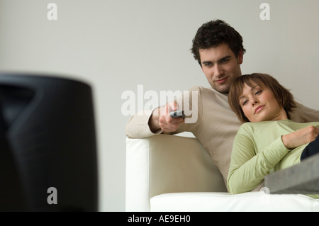 Couple allongé sur un canapé, regarder la télévision Banque D'Images