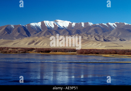 Lac gelé avec montagnes enneigées derrière à la périphérie de la prairie Sangke près de Xiahe, Gansu, Chine Banque D'Images