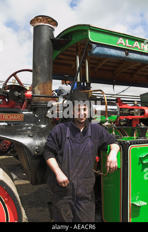 Fier exposant, en chapeau melon et en salopette, d'un moteur de traction vert à la foire annuelle de vapeur dans le village de Chipping, Lancashire, Angleterre Banque D'Images