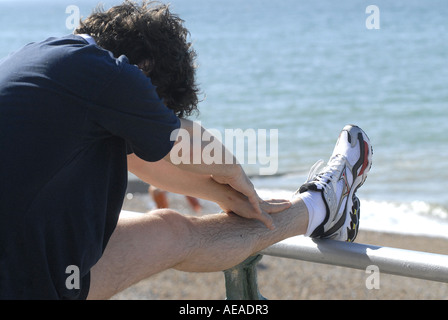 Détail D'UN HOMME des étirements pendant que courir sur la promenade du bord de mer Banque D'Images